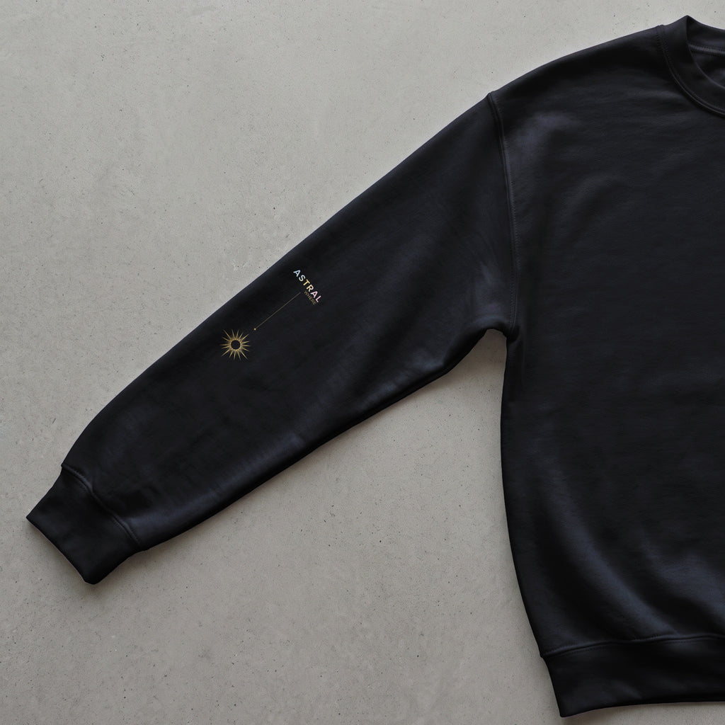 Black sweatshirt with gold sun graphic and "ASTRAL WHERE" text on the sleeve.